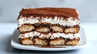 Classic tiramisu dessert with layers of coffee-soaked ladyfingers, mascarpone cream and cocoa powder dusting served on white plate for cafes and restaurants.