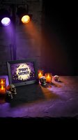 Halloween marketing display with laptop showing spooky savings promotion surrounded by decorative skulls and glowing candles in atmospheric lighting.