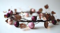 Autumn wreath with purple ornaments and dried leaves on white background. Seasonal holiday decoration for Christmas crafts and festive home decor projects.