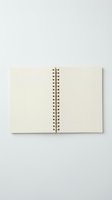 Open spiral-bound notebook with blank cream pages and black metal coil binding, displayed flat on neutral background for stationery, office supplies, and writing projects.