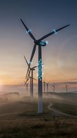 Wind turbines with glowing blue lights at sunrise generating renewable energy on rolling hills with misty landscape and dramatic sky for sustainability concepts.