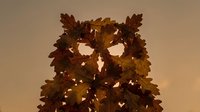 Autumn owl silhouette made from colorful fall leaves in warm brown and golden tones against neutral background for seasonal decoration projects.