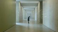 Long corridor with modern minimalist design, fluorescent ceiling lights, and pale green walls. Solitary figure in dark clothing walking through empty hallway. Suitable for corporate, architectural, and conceptual projects.