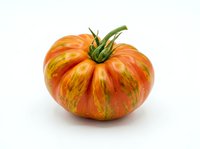 Fresh ripe heirloom tomato with vibrant orange and red striped pattern, isolated on white background for culinary and food design projects.