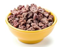 Dark chocolate chunks in bright yellow ceramic bowl on white background, macro food photography for culinary blogs and confectionery advertising.