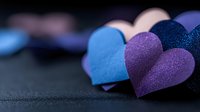 Colorful paper hearts in blue and purple shades on dark background with selective focus, romantic mood for valentines day cards and love concepts.