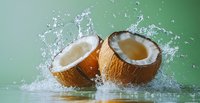 Fresh coconut halves with splashing water and dynamic motion on green background, tropical fruit with white flesh and natural juice for healthy eating.