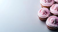 Chocolate cupcakes with pink buttercream frosting and sprinkles arranged on light background with copy space for text, top view angle for food photography.