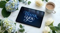 Digital tablet displaying thank you message surrounded by blue hydrangea flowers, white roses and coffee cup on marble surface for gratitude concepts.