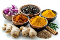 Colorful aromatic spices and fresh ingredients including turmeric, black pepper, ginger root, red onion and cinnamon in rustic bowls perfect for cooking and food photography.
