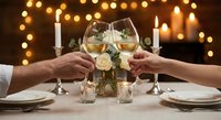 Romantic dinner date with couple toasting champagne glasses over candlelit table with warm bokeh lights creating intimate dining atmosphere.