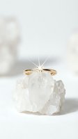 Elegant gold engagement ring with sparkling diamond displayed on raw crystal quartz stone against soft neutral background for luxury jewelry marketing.