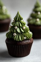 Festive chocolate cupcake with green matcha frosting piped in Christmas tree shape, decorated with silver pearl sprinkles for holiday dessert table.