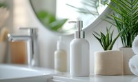 White ceramic soap dispenser on bathroom counter with towels, houseplants and modern faucet in bright minimalist interior setting, wellness and spa concept.