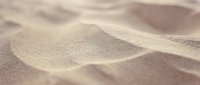 Soft golden sand dunes with gentle curves and natural texture creating abstract desert landscape patterns for backgrounds and nature concepts.