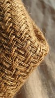Natural jute rope with detailed woven texture and frayed edges on rustic wooden surface for crafting and decorative projects.