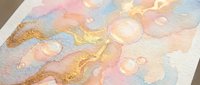 Abstract watercolor painting with golden glitter accents and soft pastel colors including pink, blue, and peach tones on textured paper for artistic projects.