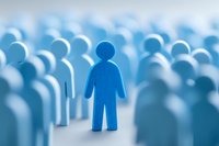 Blue wooden figure standing out from crowd, symbolizing individuality, leadership, and uniqueness in business or social environment.