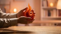 Hands holding glowing orange flame with warm interior lighting and blurred background, suitable for concepts of energy, hope, warmth, protection, spirituality, and renewable power sources.