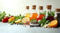 Assorted glass bottles with cork stoppers containing oils and vinegars, surrounded by fresh vegetables, citrus fruits, herbs, and peppercorns for cooking and culinary use.