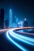 Modern cityscape with glowing light trails from traffic against illuminated skyscrapers at night, creating futuristic urban atmosphere with blue tones.