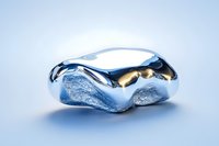 Shiny metallic abstract sculpture with smooth liquid-like curves and golden accents on light background, modern art piece showcasing flowing organic forms.