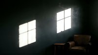 Dark interior room with two bright window frames casting geometric light patterns on concrete wall, featuring brown leather armchair and side table for modern loft, industrial design, and architectural photography.