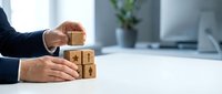 Businessman hands arranging wooden blocks with star rating symbols on office desk for customer feedback and quality evaluation in corporate environment.