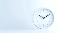 Minimalist white wall clock showing ten past ten against light background with copy space, modern interior design element for office and home decor.