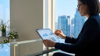 Professional businesswoman analyzing financial data on tablet in modern office with city skyline view for corporate presentations and reports.