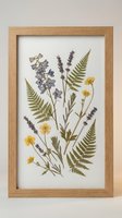 Pressed flower botanical art in wooden frame featuring ferns, lavender and yellow wildflowers on white background for home decor and wall art display.