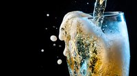 Refreshing sparkling water or champagne pouring into glass with bubbles and splash against black background for beverage advertising and celebration concepts.