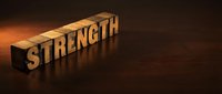 Wooden blocks spelling STRENGTH on a dark mahogany surface with dramatic warm lighting, conveying power and motivation for business or wellness projects.