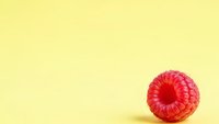 Fresh red raspberry on bright yellow background with copy space for healthy food and nutrition concepts.