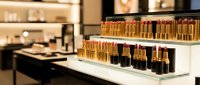 Luxury cosmetics display with golden lipstick collection arranged on white shelves in upscale beauty store interior for premium makeup retail marketing.