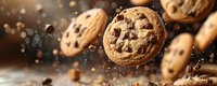 Freshly baked chocolate chip cookies with crispy edges and gooey centers, floating in dynamic composition with scattered chocolate pieces and crumbs.