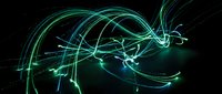 Abstract green and blue light trails creating flowing energy waves on black background for digital art and futuristic design projects.