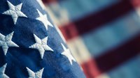 Close-up of American flag stars on blue field with red and white stripes blurred in background, patriotic symbol for Memorial Day, Independence Day celebrations.