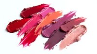 Colorful lipstick smears and makeup swatches in vibrant shades of red, pink, coral and purple on white background for cosmetic and beauty concepts.