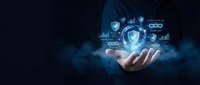 Businessman hand holding glowing shield with security icons and data protection symbols on dark blue background for cybersecurity and network safety concepts.
