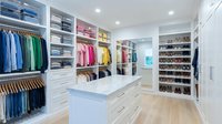 Spacious walk-in closet with white cabinetry, organized clothing racks, shelving units, and shoe display. Interior design and home organization concept.