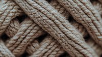 Close-up macro shot of natural beige cotton rope texture showing intricate braided pattern and fiber details, suitable for backgrounds and textile design concepts.