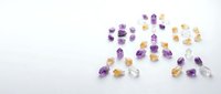Collection of colorful gemstones including amethyst, citrine and clear quartz crystals scattered on white background for jewelry making and healing.