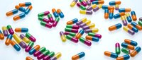 Colorful pharmaceutical capsules scattered on white background. Medical pills in vibrant colors including blue, green, pink, yellow and orange for healthcare concepts.