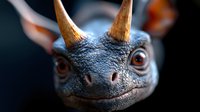 Closeup portrait of fantasy dragon creature with amber eyes, textured blue-gray scales and golden horns against dark background. Suitable for game design and book covers.
