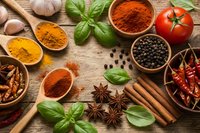 Colorful aromatic spices, herbs and seasonings on rustic wooden table. Turmeric, paprika, pepper, cinnamon, basil, chili, tomato and garlic for cooking.