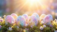 Colorful painted Easter eggs nestled in green moss with small white flowers against warm sunlight and bokeh background for spring holiday celebrations.