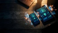 Mobile cybersecurity shield protection on smartphone and tablet screens with glowing digital security icons on wooden desk background.