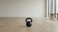 Black kettlebell weight on wooden floor in minimalist gym space, suitable for fitness, training, and wellness content.