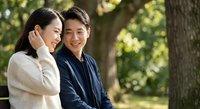 Happy Asian couple enjoying romantic moment together in sunny park setting with natural green foliage background for lifestyle and relationship content.